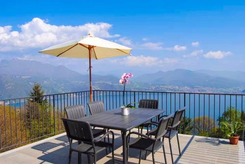 a table with chairs and an umbrella on a balcony at Perla del Lago in Carmine