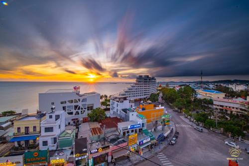 a city with a cruise ship in the ocean at sunset at Monaco Hotel Phú Quốc in Phu Quoc