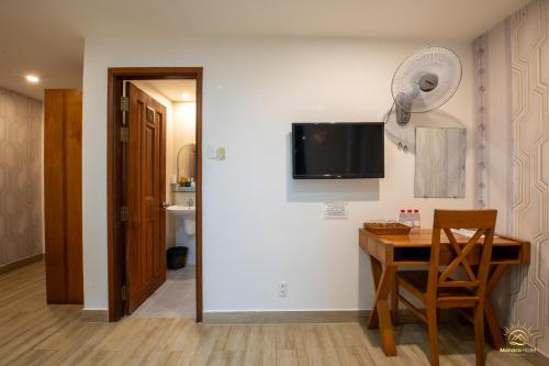 a dining room with a table and a tv on a wall at Monaco Hotel Phú Quốc in Phu Quoc