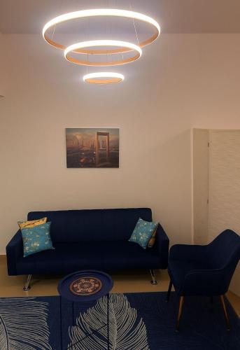 a living room with a blue couch and a chandelier at LA MAISON, Horizon Towers,AJMAN in Ajman