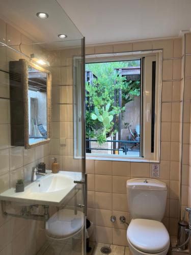 a bathroom with a toilet and a sink and a window at Daphne Glyfada Corfu in Glyfada