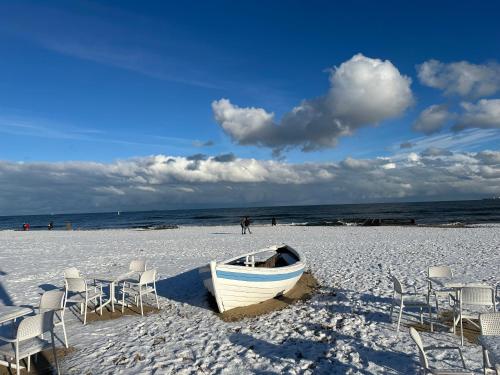 a boat sitting on a beach with chairs and the ocean at Nice Sopot in Sopot