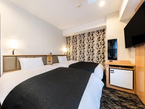 a hotel room with two beds and a flat screen tv at APA Hotel Kagoshima Chuo Ekimae in Kagoshima