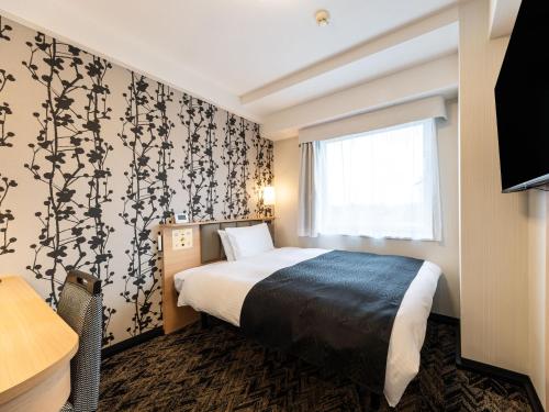 a hotel room with a bed and a window at APA Hotel Kagoshima Chuo Ekimae in Kagoshima