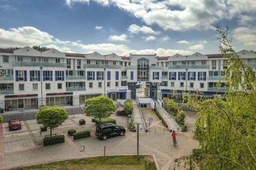 a large white building with a car parked in a courtyard at Deichperle im Aparthotel Zingst in Zingst
