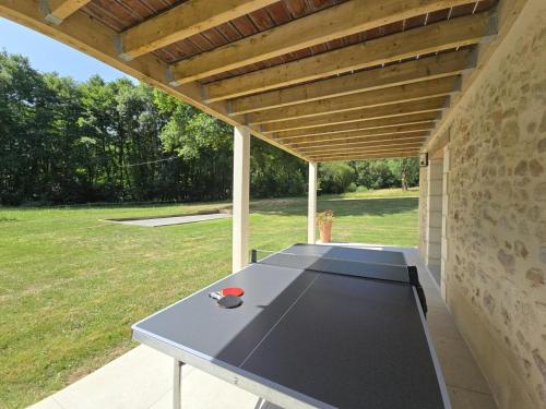 a ping pong table sitting under a wooden roof at La maison d'elena in Thiviers
