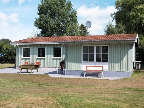 a green and white building with a picnic table and benches at 8 person holiday home in Stege-By Traum in Stege