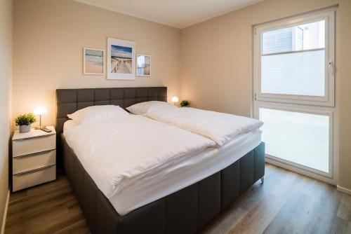 a large bed in a bedroom with a window at "Coast & Cosy" in Tossenserdeich