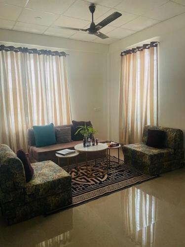 a living room with two chairs and a couch and a table at Karma Service Apartment in Jaigaon