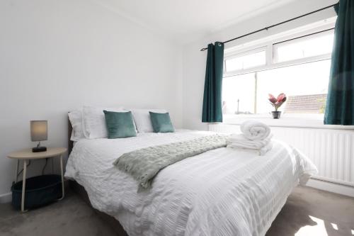 a white bedroom with a bed and a window at King Beds - Dining Space - Ev Charger - Coffee - Contractor & Families in Coity