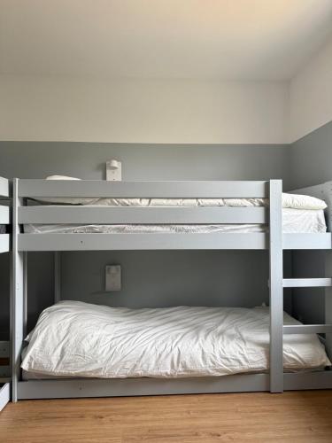 a bedroom with two bunk beds with white sheets at Le Logis du Chêne - Piscine, proche Futuroscope in Vendeuvre-du-Poitou