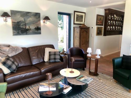 a living room with a brown leather couch and chairs at Villa Tidinghi, plage de Rospico à pied in Névez