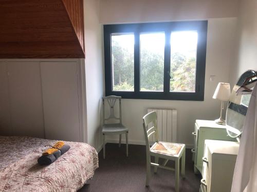 a bedroom with a bed and a chair and a window at Villa Tidinghi, plage de Rospico à pied in Névez