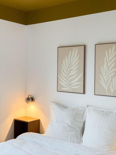 a bedroom with a white bed with two pictures on the wall at Le Logis du Chêne - Piscine, proche Futuroscope in Vendeuvre-du-Poitou