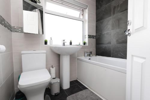a bathroom with a toilet and a sink and a bath tub at King Beds - Dining Space - Ev Charger - Coffee - Contractor & Families in Coity