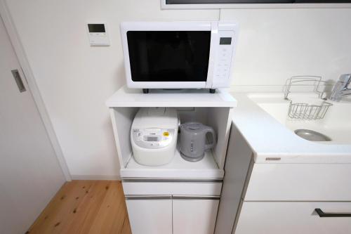 a white kitchen with a microwave and a computer monitor at The CATAN 久美浜 in Kyotango