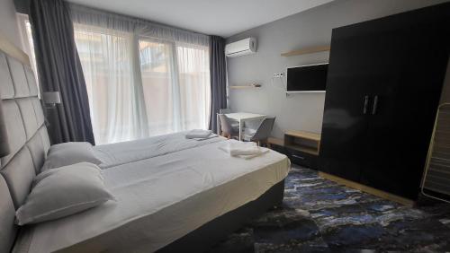 a bedroom with a large bed and a window at Marina Beach Apartments Pomorie in Pomorie