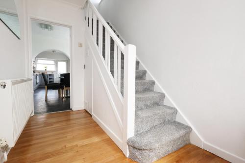 a staircase in a home with white walls and wood floors at King Beds - Dining Space - Ev Charger - Coffee - Contractor & Families in Coity