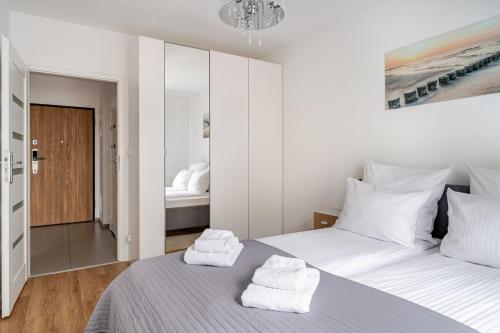 een witte slaapkamer met een bed met handdoeken erop bij MiCasaEsSuCasa with free parking! in Gdańsk