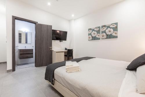 a white bedroom with a bed and a kitchen at Guesthouse No. 48 in Msida