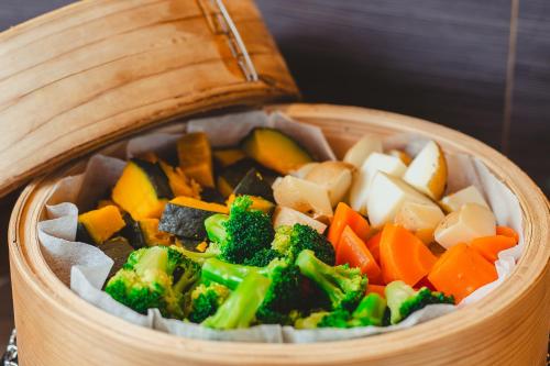 a wooden bowl filled with vegetables in a wooden bowl at Hotel La'gent Plaza Hakodate Hokuto in Hokuto