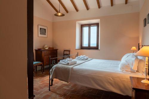 キアンチャーノ・テルメにあるCountry House Podere I Pratiのベッドと机と窓のある寝室