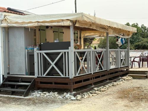 a small house with a porch with a tent at Maison ensoleillée à Saint-Pierre-d'Oléron avec piscine partagée in Saint-Pierre-dʼOléron