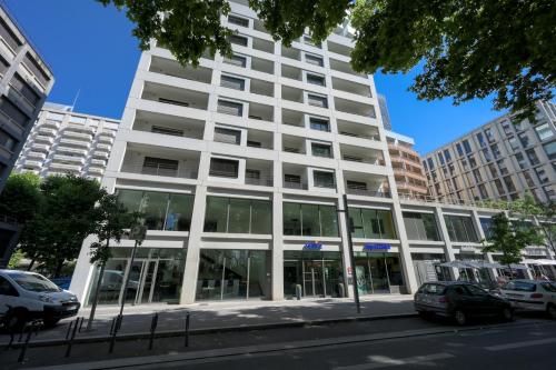a large white building with windows on a city street at Nemea Appart Hotel So Cloud Lyon Gare Part-Dieu in Lyon