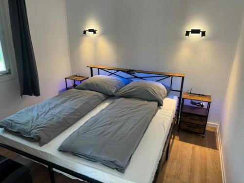 a bed in a bedroom with two lights on the wall at Feriendorf Seddiner See - Bungalow 4 in Seddin