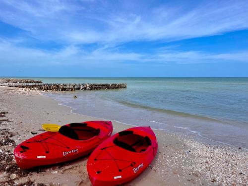two red kayaks sitting on a beach near the water at Beachfront House with Terrace & Bar, AC, 6 Max in Chuburná