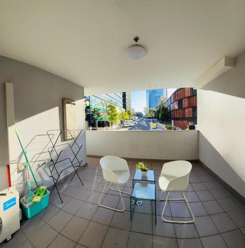 a balcony with white chairs and a table and a window at Parramatta Adorable 3Br Apt ParkingBusShopping in Sydney