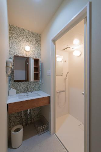a bathroom with a sink and a shower with a mirror at guesthouse YAWNYAWN in Echizen