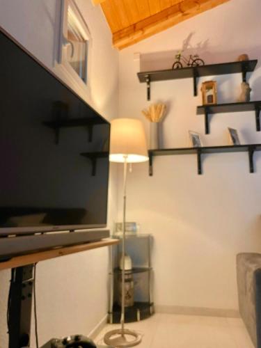 a room with a tv and a lamp and shelves at Swiss Escape, Chalet with Private Spa & Easy Train Access in Frinvillier