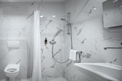 a white bathroom with a shower and a toilet at Astoria Hotel in Prague