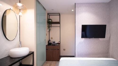 a bedroom with a bed and a tv on a wall at Hotel Calmo Hamilton in Singapore