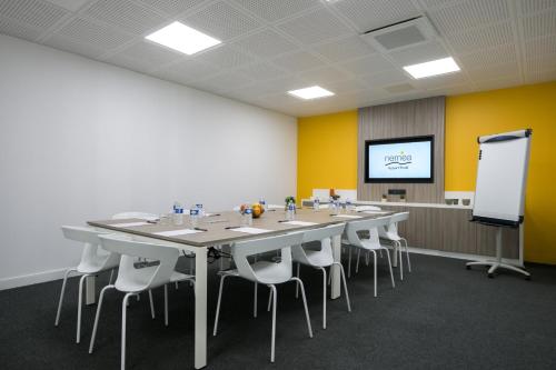 a conference room with a long table and chairs and a screen at Nemea Appart Hotel So Cloud Lyon Gare Part-Dieu in Lyon