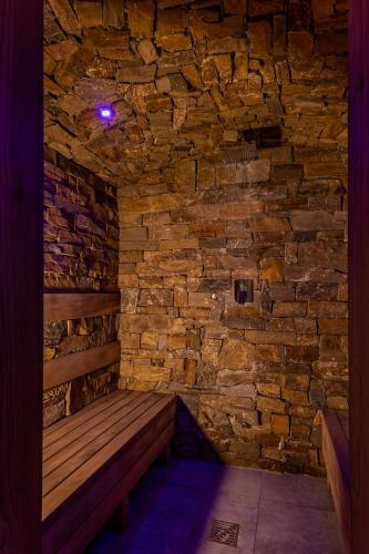 a wooden bench in a room with a stone wall at CHATA POD PRZEHYBĄ in Stary Sącz