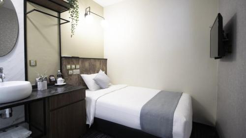 a bedroom with a bed and a sink and a mirror at Hotel Calmo Hamilton in Singapore