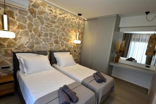 two beds in a room with a stone wall at Villa 101 Rhodes in Ixia