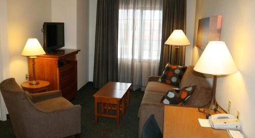 a hotel room with a couch and chairs and a television at Staybridge Suites Minneapolis-Maple Grove by IHG in Maple Grove