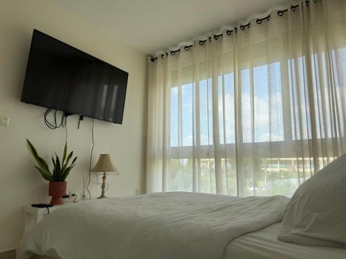 a bedroom with a bed and a large window at חופשה חלומית in Caesarea