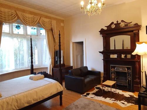 Grandview House Private 2Bed 2Bath Melb Airport في ملبورن: غرفة نوم بسرير وكرسي ومدفأة