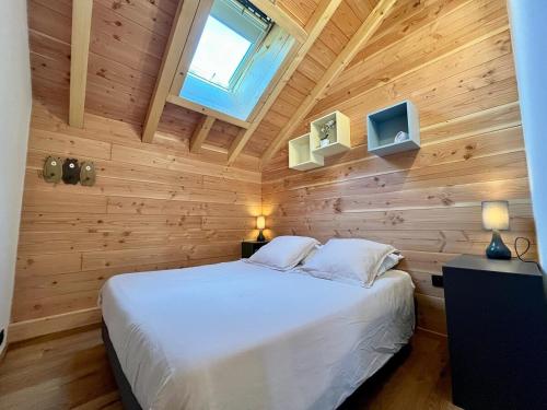 ein Schlafzimmer mit einem weißen Bett an einer Holzwand in der Unterkunft Le Dahu - Venosc, Les Deux Alpes in Les Granges