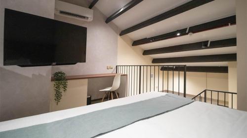 a bedroom with a bed and a flat screen tv at Hotel Calmo Hamilton in Singapore