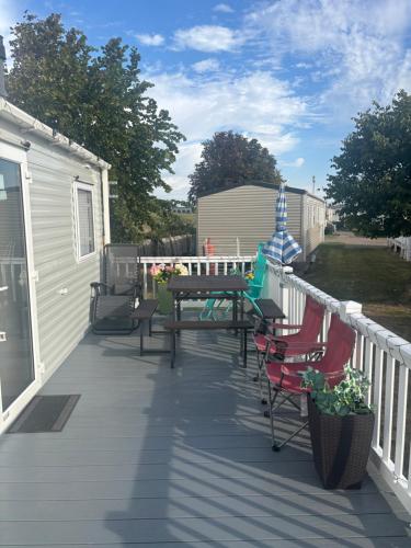 a deck with a picnic table and chairs on a house at Singh&Leite Family caravan for 10 people with 2toilets and lovely Decking in Jaywick Sands