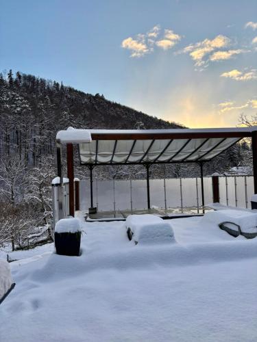 a covered area with snow on the ground at Swiss Escape, Chalet with Private Spa & Easy Train Access in Frinvillier