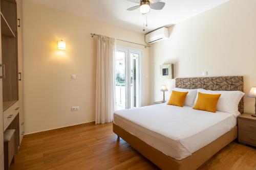a bedroom with a large white bed with orange pillows at Avia Blue Maisonettes - Messinia Gulf Retreat in Avia