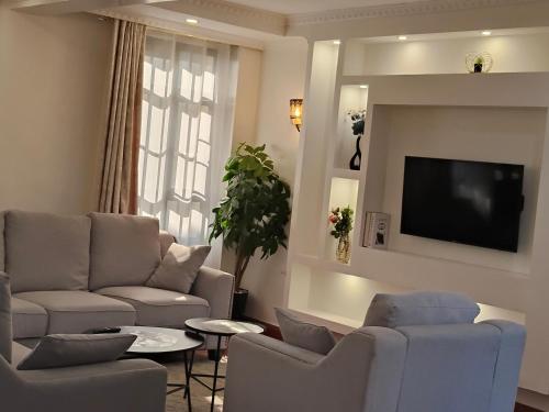 a living room with a couch and a tv on a wall at 3 Bedroom with SQ Simba in Naivasha