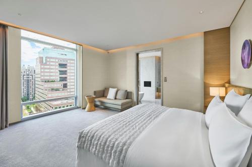a bedroom with a large bed and a large window at Le Meridien Taipei in Taipei