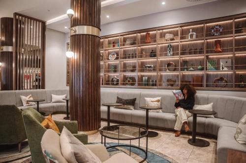 a woman sitting on a couch in a waiting room at Radisson Hotel Cape Town Foreshore in Cape Town